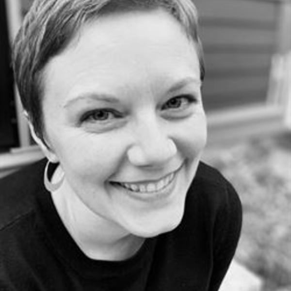 Headshot of Lisa Purcell. Black and White filter. Lisa is smiling while sitting on the front step of a house