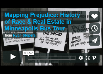 Still from a video with text: "Mapping Prejudice: History of Race & Real Estate in Minneapolis Bus Tour" from Ryan Stopera and picketing signs in the background.
