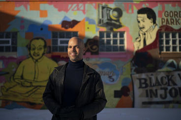 Dan Bergin standing in front of a graffiti wall in a black leather jacket and turtleneck