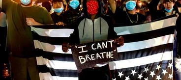 Masked protestors holding an upside down american flag and a sign saying "I Can't Breathe"